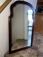 Front view of entire wooden arched mirror leaning against wall