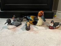 Front view of five carved painted wooden duck figures of varying sizes