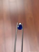 Front view of pear-cut sapphire held in tweezers