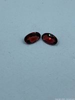 Pair of oval red garnets side-by-side on light background