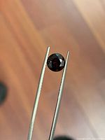 Front view of faceted garnet held in tweezers