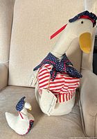 Large and small stuffed ducks on chair showing overall design and size contrast