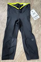 Full view of Pearl Izumi tights laid flat showing black fabric, lime waistband, reflective logo