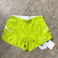 Front view of neon yellow Pearl Izumi cycling shorts with tags attached