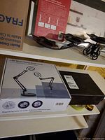 Retail box for LED magnifying desk lamp and other lot contents on shelf