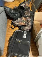 Camo duffel and black computer bag on floor