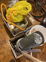 Overview of box with yellow gas connector, sink basin, insulated duct, vinyl tubing, plastic pails