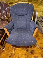 Front view of blue-upholstered wooden glider rocking chair showing seat cushion tears