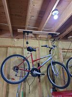 Full view of red and silver mountain bike hanging from ceiling hoist
