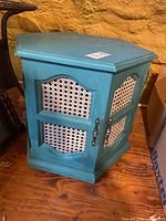 Front view of aqua blue hexagon side table with cane panel doors
