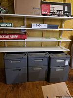 Front view of all three grey metal stacking file cabinets under shelving
