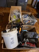 Three cardboard boxes with bucket, tool bag, packaged hardware and supplies