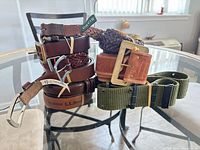 Stacked belts showing top braided brown leather belt with Orvis tag and brass buckle