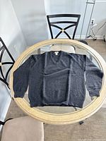 Sweater laid flat showing full front, sleeves, neckline, color and overall condition