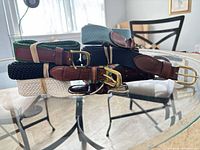 Stacked belts showing variety of materials, colours and buckles