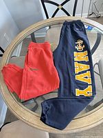 Both sweatpants laid out on table showing colors, graphics, and general condition