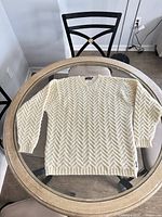 Full view of cream chevron knit sweater laid flat on table