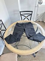 Front view of black tactical cargo pants laid flat on round glass table