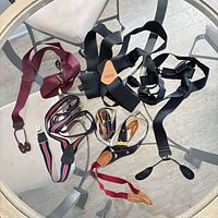 Overview of eight pairs of suspenders on glass table