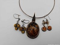 Front view of amber pendant necklace with two pairs of amber earrings