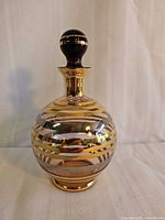 Front view of smokey amber glass decanter with stopper showing gold and silver banding