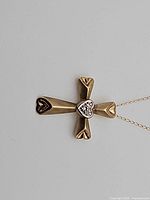 Front view of gold cross pendant showing heart center with clear stones