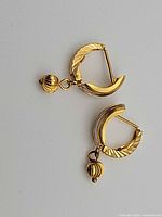 Pair of gold hoop earrings laid flat, showing design and closure