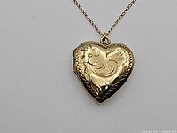 Front view of engraved gold-tone heart locket on chain