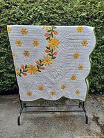 Full view of quilt on rack showing size, pattern and scalloped border