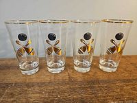 Front view of four highball glasses showing bowling graphics and gold rims