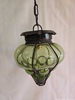 Full view of green caged glass pendant hanging by chain