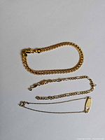 All three gold bracelets laid out: 18K curb-weave, 12K Figaro broken, 10K ID chain