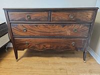 Front view showing all five drawers, brass pulls, casters, overall condition