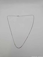 Full view of white gold chain laid flat forming a V shape