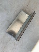 Single piece of step flashing laying flat displaying galvanized finish