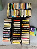Top-down view showing two layers of assorted 8-track tapes, titles and labels visible