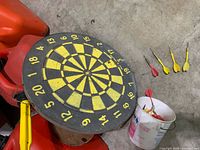 Overall lot view with dartboard, bucket of darts, loose darts
