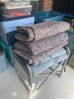 Stacked folded moving blankets on folding stool