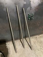 Three stainless steel rods leaning against surface