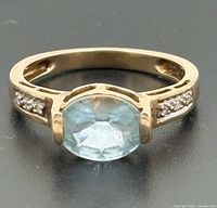 Front view of ring showing blue topaz and diamond shoulders