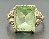 Frontal view showing emerald-cut green stone and filigree shoulders