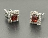 front view of both earrings showing garnet centers and diamond halos