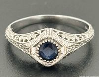 Front view of ring showing sapphire, milgrain diamond setting and filigree shoulders