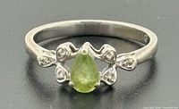 Front view showing pear-cut peridot and diamond-accented crown setting