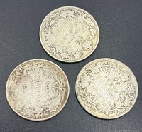 Reverse sides of three Canadian sterling silver 25-cent coins showing wreath design and dates