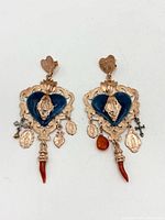 Front view of both earrings displaying blue enamel hearts, rose-gold plating, religious charms, and red coral drops