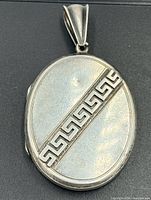 Front of oval locket showing Greek key design and bail