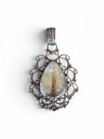 Front view of pendant showing rutilated quartz cabochon and filigree frame