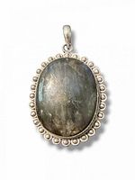 Front view of oval labradorite pendant showing beaded silver border and integrated bail