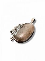 Front view of pendant showing rutilated quartz cabochon and decorative silver motif
